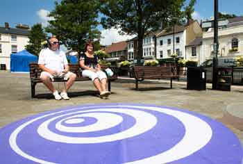 Two people on the bench in front of graphic