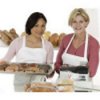 Two women holding trays of baked goods