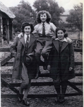 Lily Kemble, Dora Boase and another land girl on gate at Hasells Hall